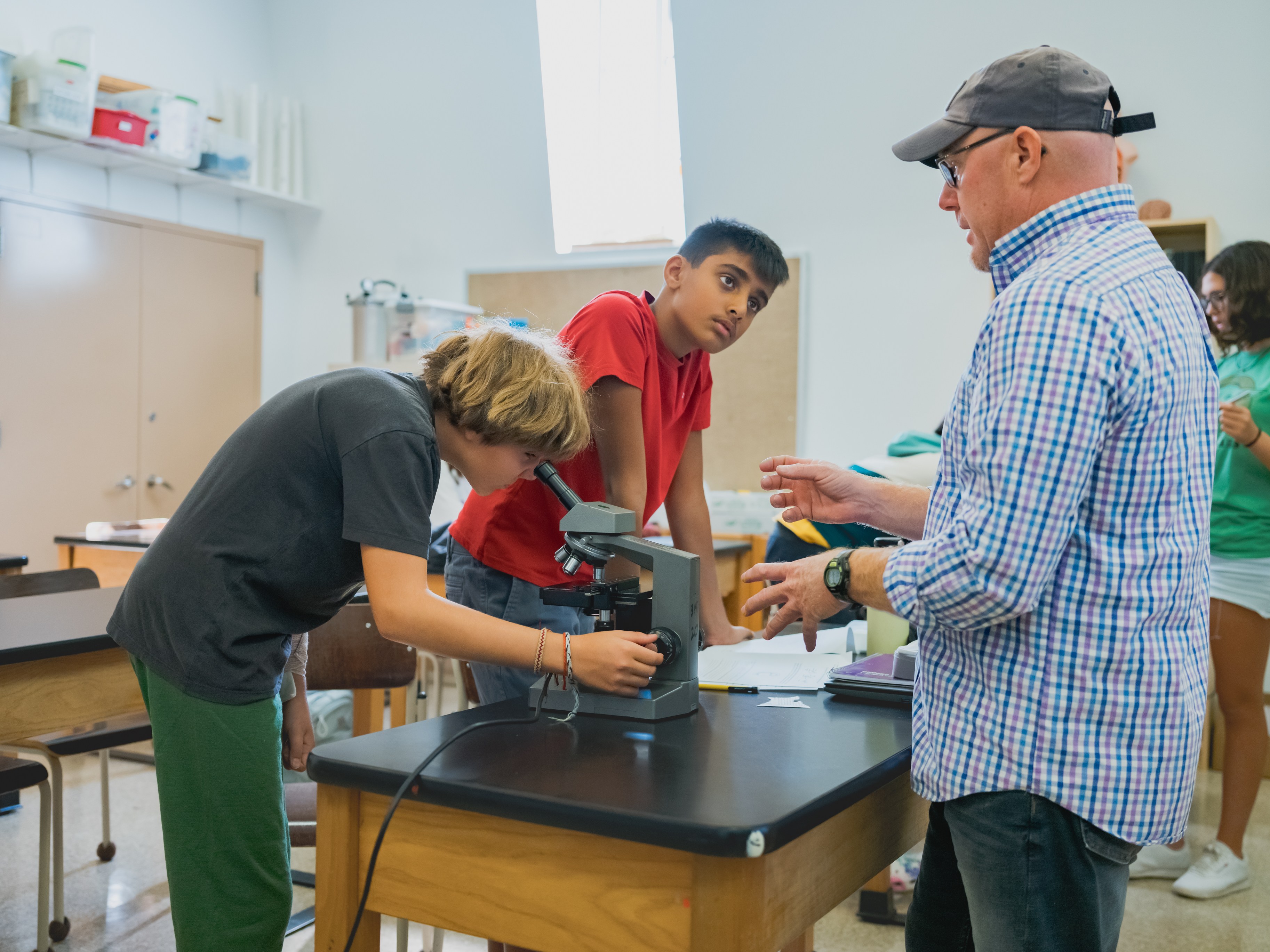 Students learning with microscope guided by teacher